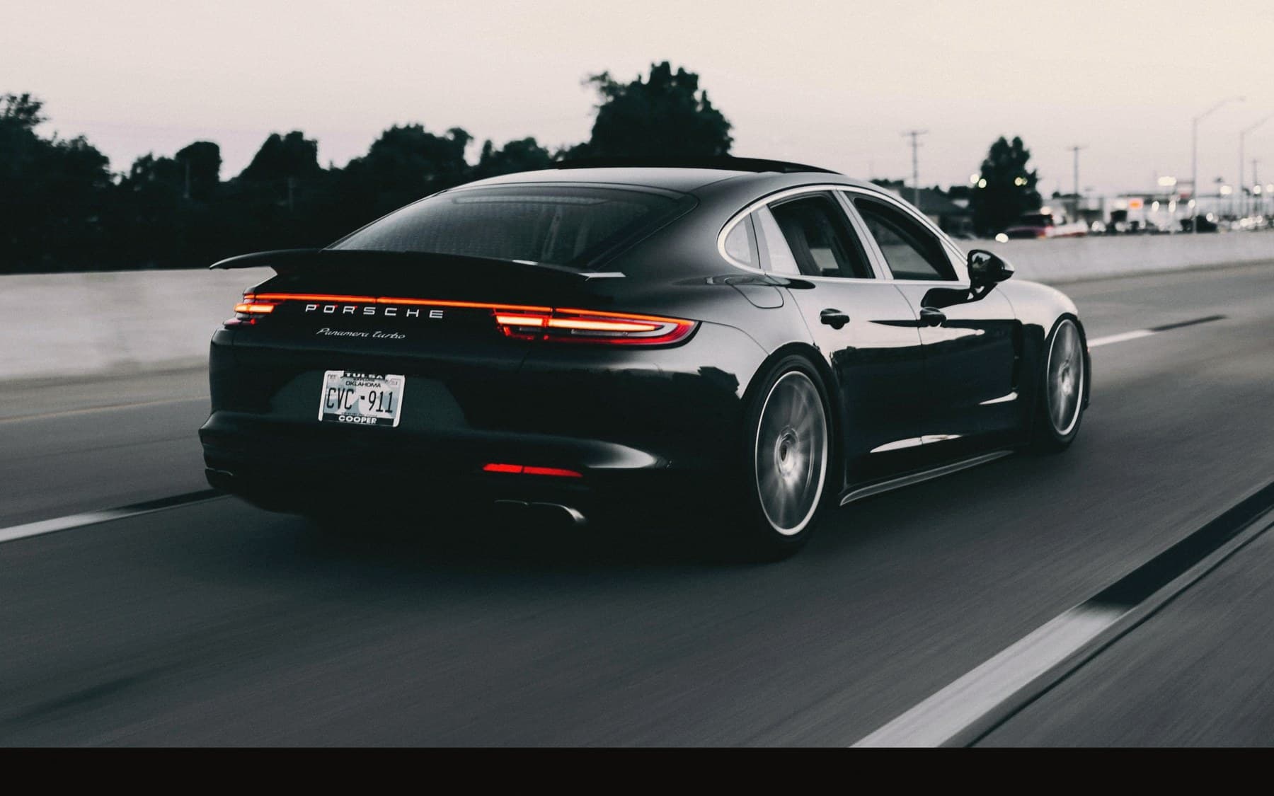Porsche noire garée devant une façade en briques, lumière de fin de journée